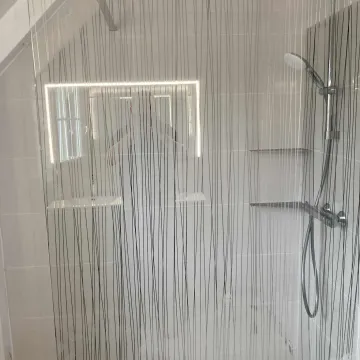 Pose d’une douche avec paroi vitrée, colonne de douche et rangements intégrés – rénovation de salle de bain